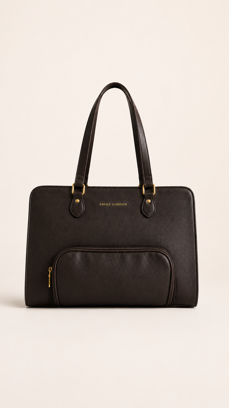 A black leather tote bag with double top handles, a front zippered pocket, and gold-tone hardware, photographed against a solid light beige background.